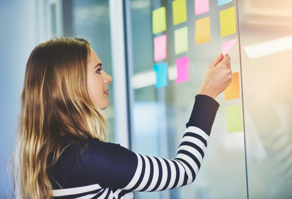 office lady adding sticky notes on office board